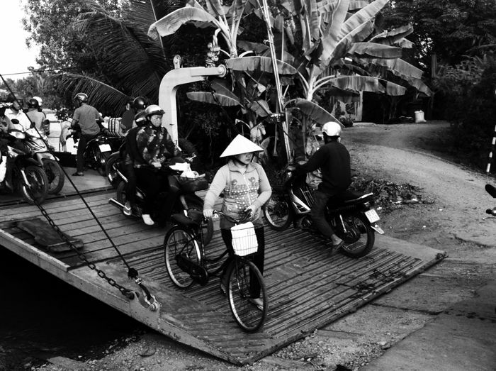 A black and white smartphotne street photo of people walking off a ferry with bicycles