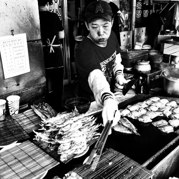 black and white smartphotne street photo of a market vendor frying fish