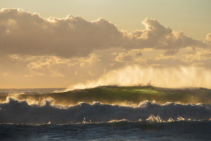 Sunrise seascape with unrest sea and green water and beautiful incoming backlit waves - water photography settings