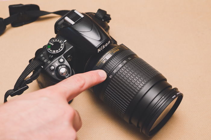 A person pointing to autofocus mode on a Nikon DSLR