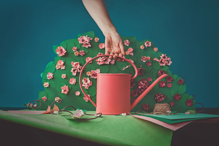 Fun photography still life of a person holding a craft watering can featuring opposite colors red and green