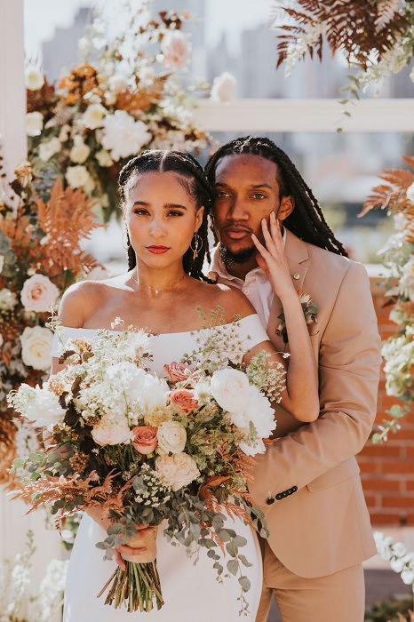 Bride and groom with floral display from Green Wedding Shoes's wedding blog