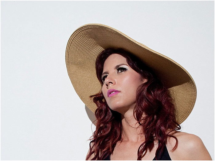 A female model posing in a straw hat for a beauty photo shoot