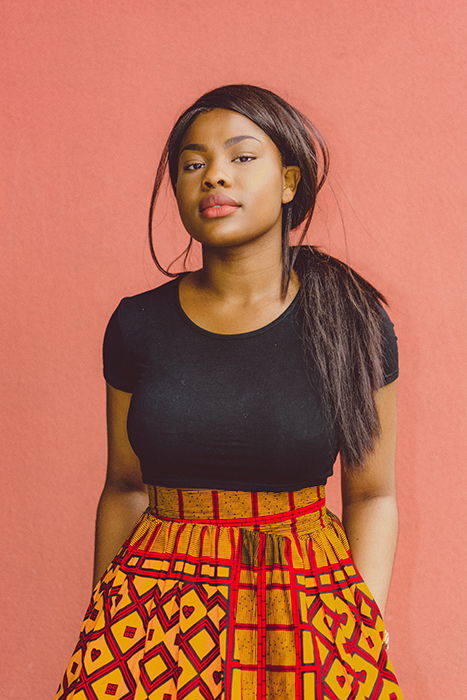 A female posing in front of a red wall