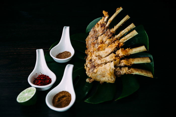 A restaurant photography shoot of a plate of food and spices against a dark background