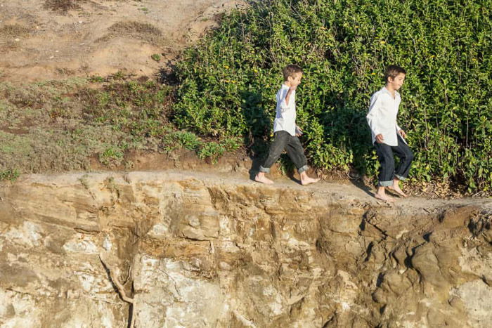 A sweet family beach pictures shot of two young boys walking around the beach in matching outfits