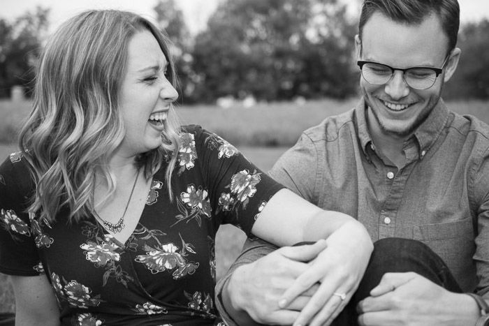 A couple laughing and holding hands in a natural relaxed pose in an outdoor setting