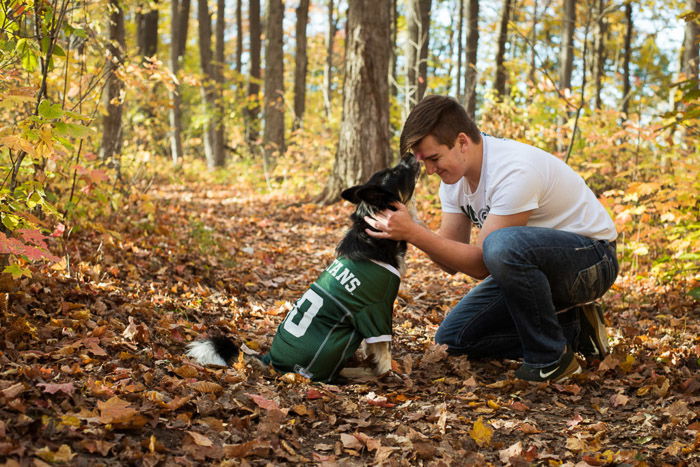 A man in a forest holding his dog in a relaxed pose