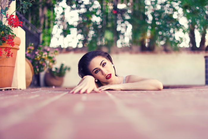 A creative portrait photo of a female model arising from pink floorboards