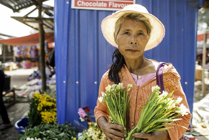  A photo of a female market vendor selling flowers, how to create white background photography