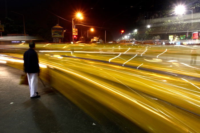 A person walking through a busy street at night using long exposure camera settings for street photography