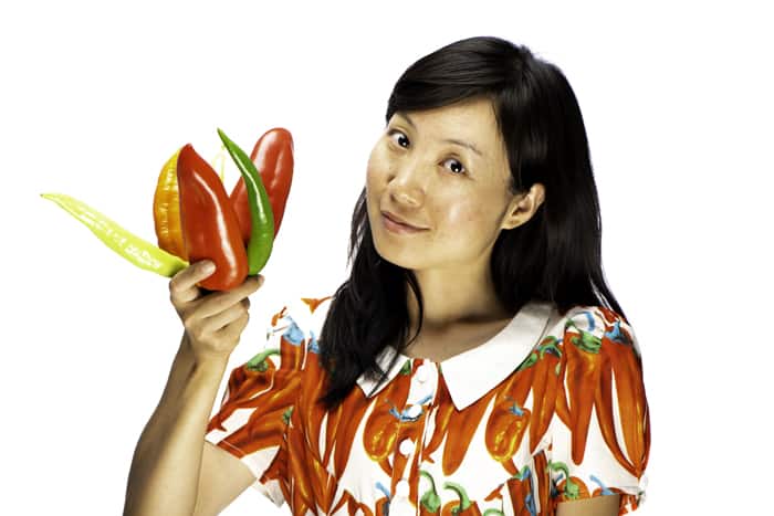 portrait of a female model holding chillis against a white photography background