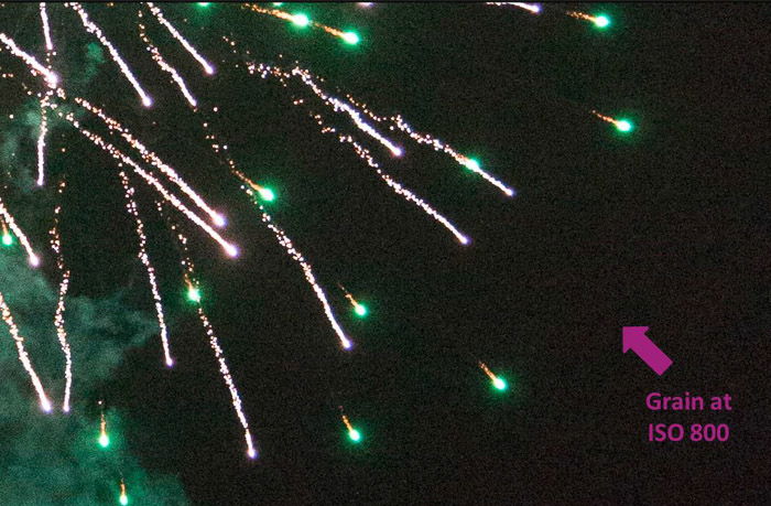 Close-up of fireworks with an arrow pointing out grain in the photo to learn DSLR basics