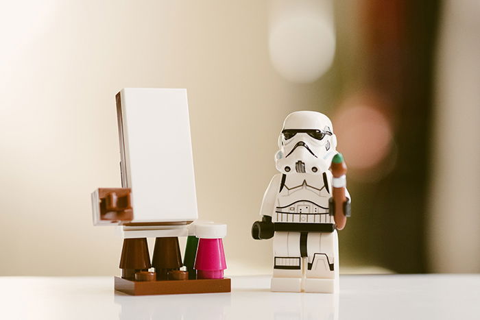 Cool close up toy photography of a lego storm trooper painting on a toy easel