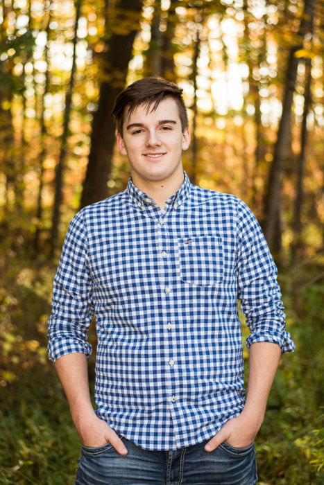 A portrait of a young man posing in a forest with beautiful background blur