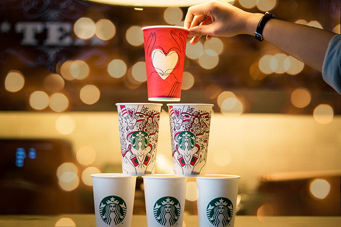 A stack of Christmas themed cups with bokeh lights in the background