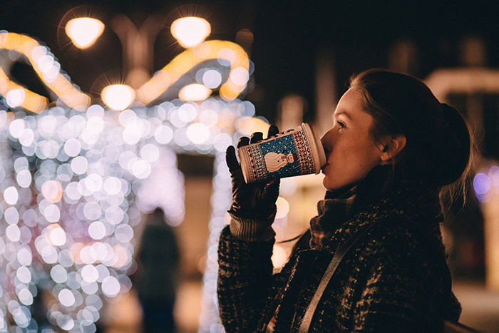 Beautiful Christmas bokeh lights in the background of a portrait of a girl drinking coffee