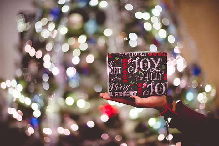 Beautiful Christmas bokeh lights in the background of a person holding a gift