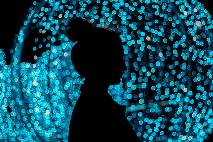 A persons silhouette with blue Christmas bokeh lights background