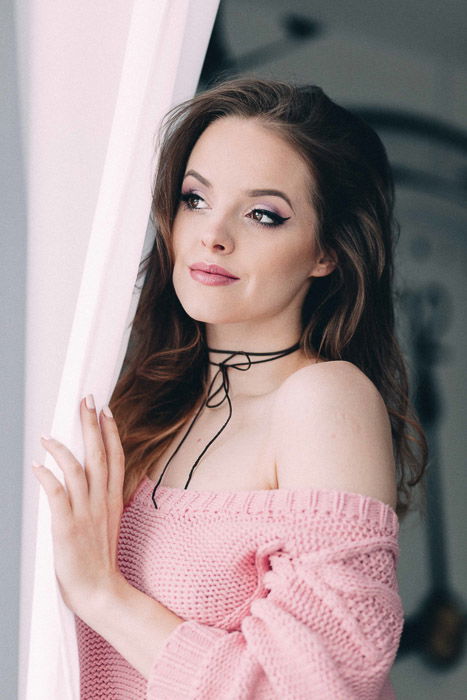 Bright and airy glamour shots of a female model posing by a curtain