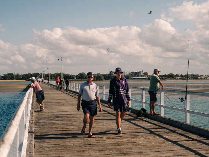 A wooden promenade with many people walking or standing