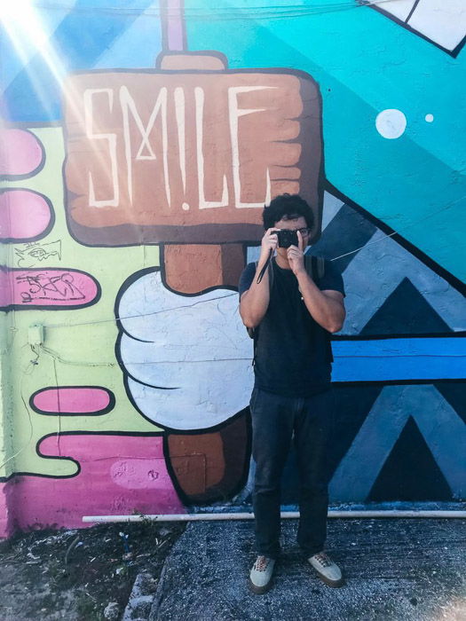 A person posing with a camera in front of another camera taking the selfiwe by using an iPhone camera timer and tripod