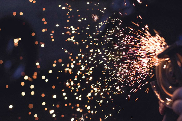 Close up shot of sparks flying from industrial machinery in low light