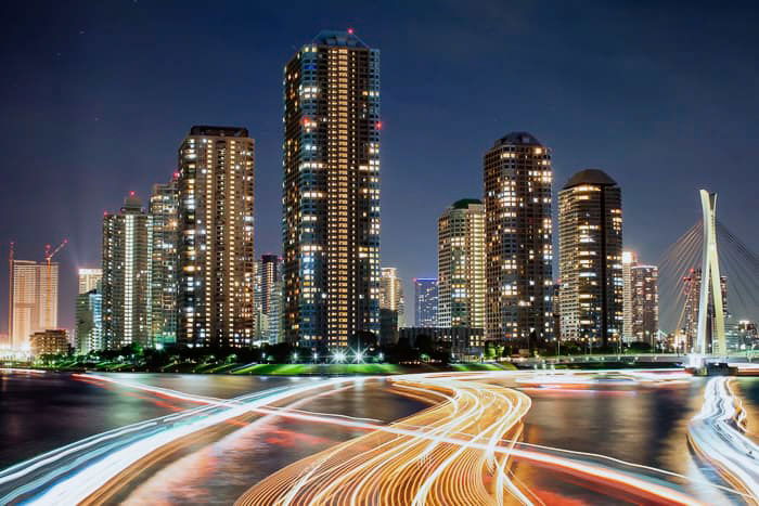 A sprawling cityscape with streaming colored light trails