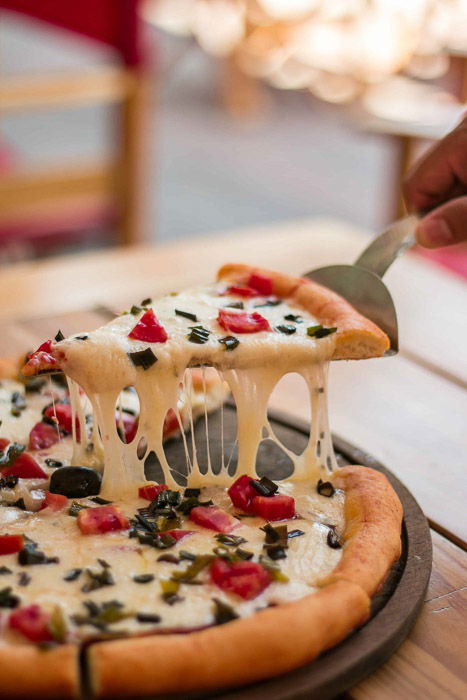 A close up of a person taking a slice of pizza