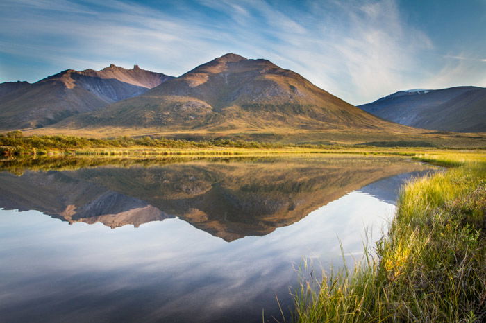 A stunning autumn landscape shot of mountains reflected in water below