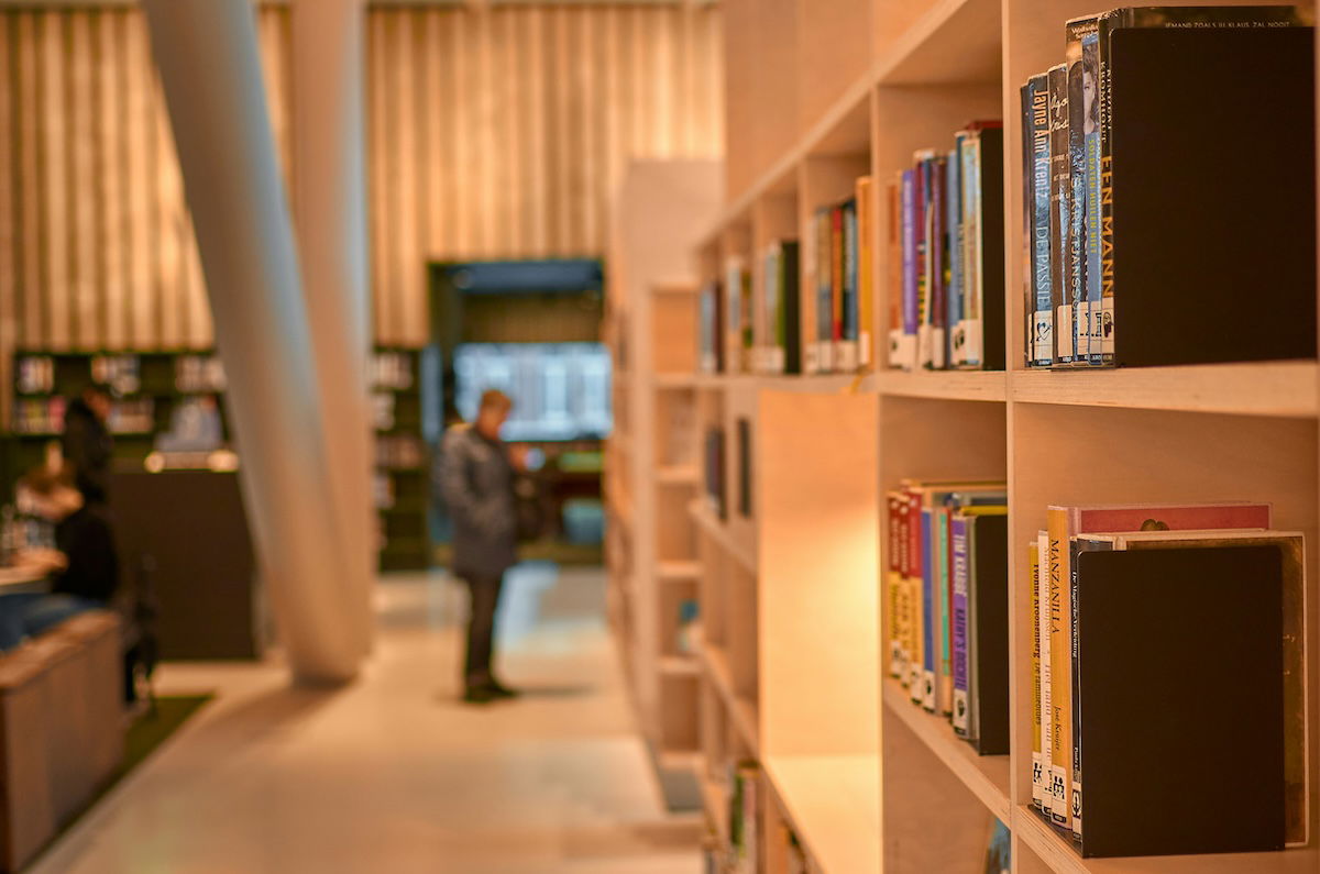 A bookshelf with books and a blurry person in the background to show an asymmetrical photo