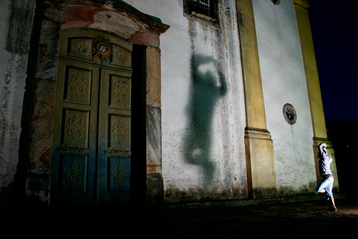 A person standing on one leg in front of a large building with their shadow on a wall to show balance in photography