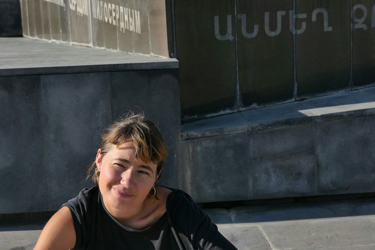 An asymmetrical portrait of a woman outside with a concrete wall in the background