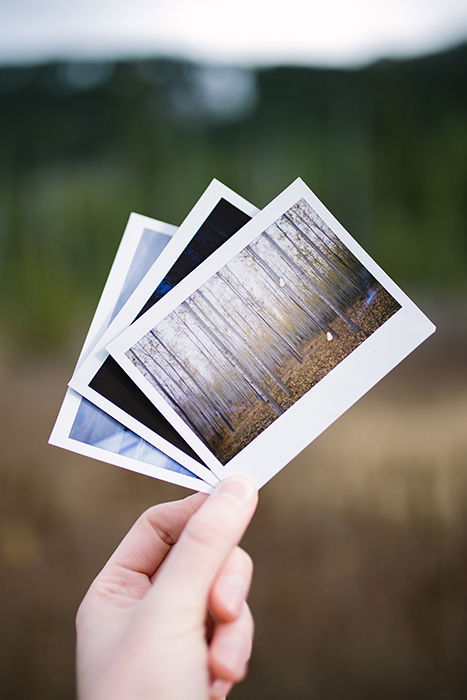 A person holding three polaroid photos - film photography look