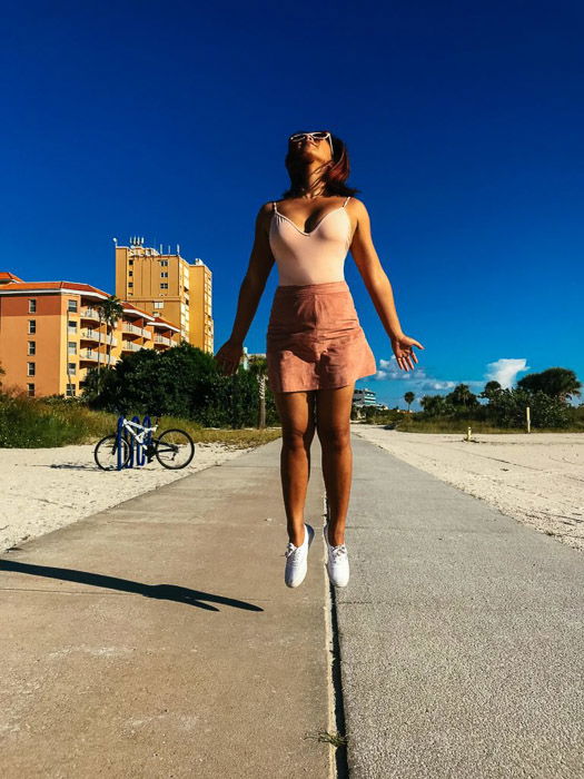 An outdoor photo of a girl jumping on a pavement shot using iPhone burst mode