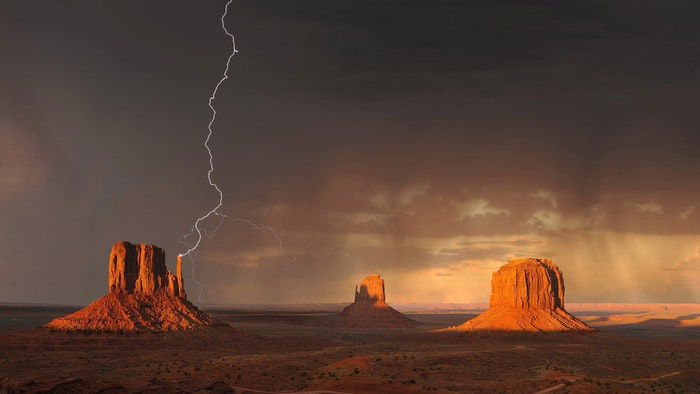 Forked lighting striking over a desert landscape at night