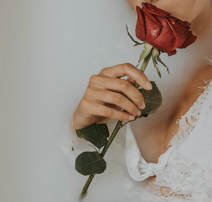 Close up Milk bath photography shot of a female model holding flowers