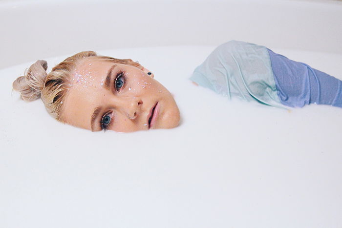 A beautiful milk bath photography portrait of a female model with glitter on her face