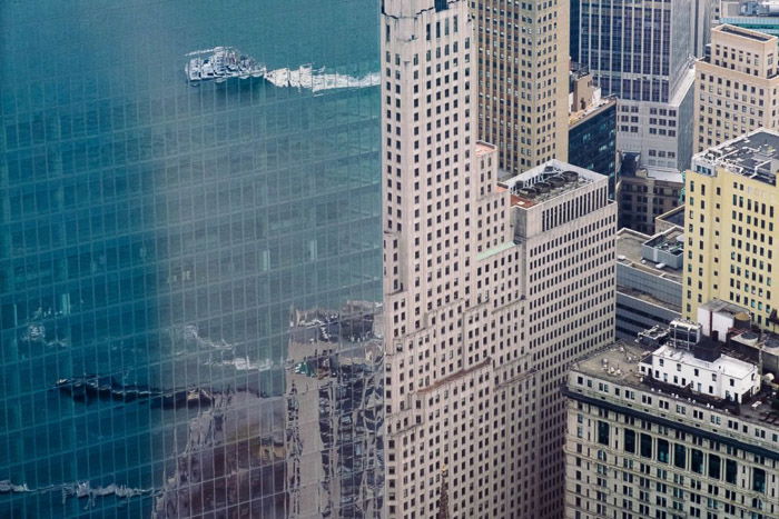 Aerial cityscape with buildings and sea reflected in the glass windows of a neighbouring building - reflection photography tips