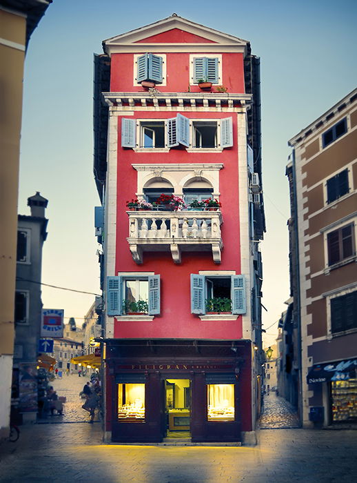 A quaint red building stands out because of its symmetry, vibrant colors, and warm lights