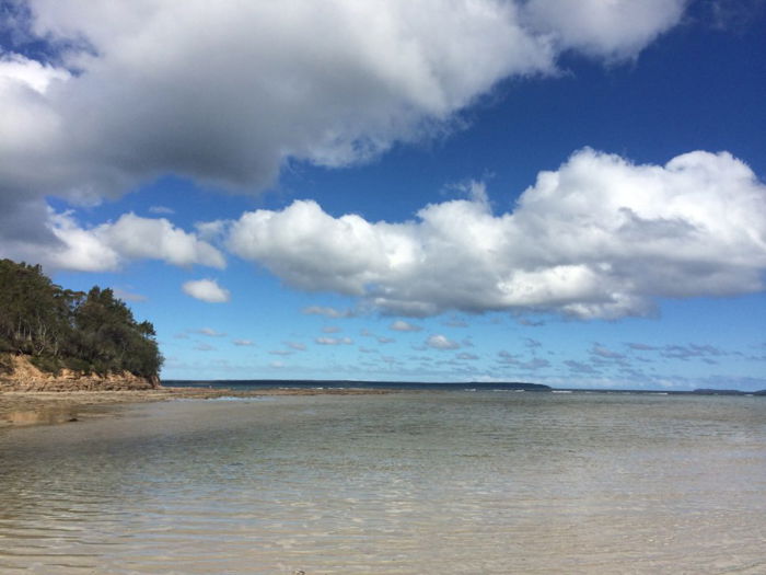 calm clear waters of beach and big clouds in blue sky