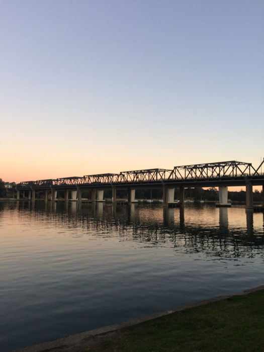 silhouette of a long bridge over water at sunset