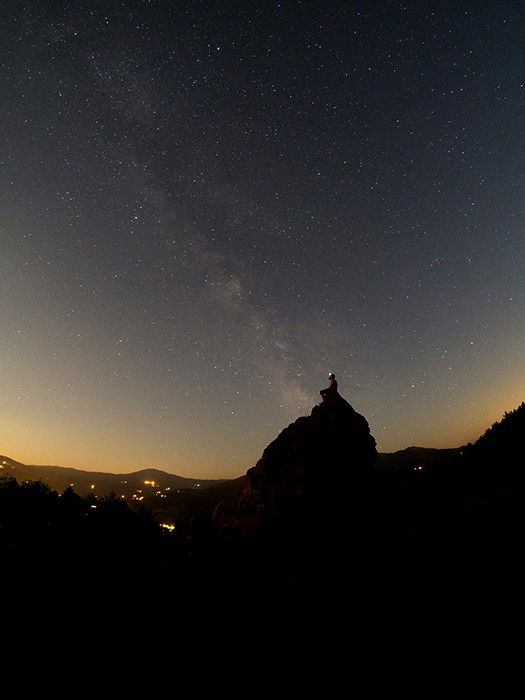 A man sitting on a rock under an impressive star filled sky