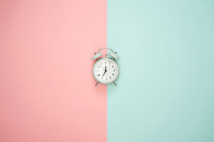 A quirky product shot of an alarm clock demonstrating symmetry in photography due to the central composition and split color background