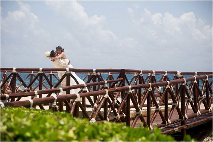 A newlywed couple embracing on a wooden bridge