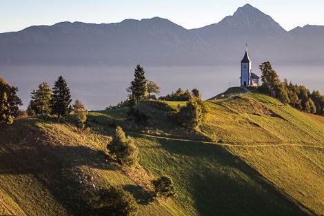 A beautiful landscape in the mountains, with a church on a hill. 