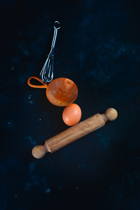 Setup for shooting a still life of a hand balancing kitchen utensils and flour clouds 