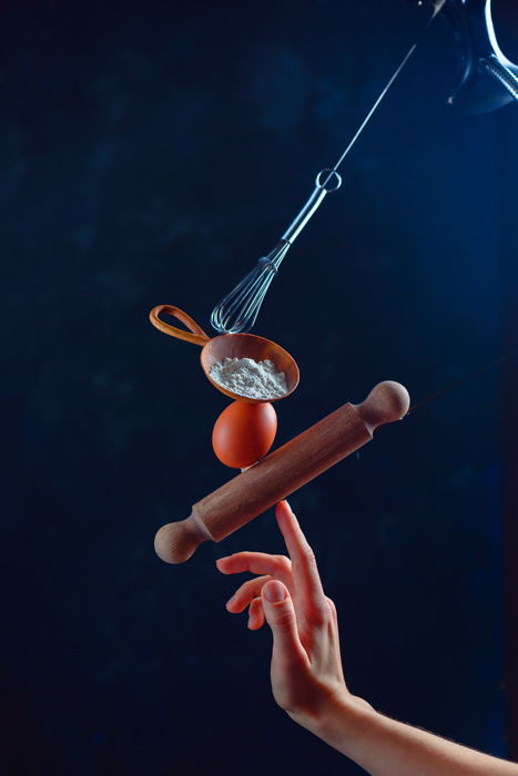 A still life of a hand balancing kitchen utensils