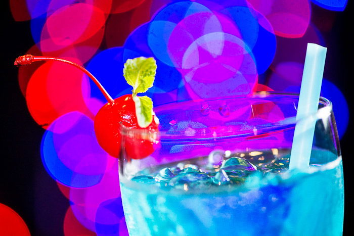 A close-up of a blue cocktail with blurry bokeh light background