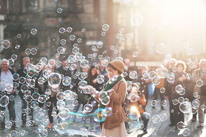 A street photography shot of a woman playing with bubbles outdoors 